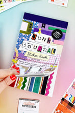 Load image into Gallery viewer, Hand holding a 'Junk Journal' sticker book with colorful designs on a pastel background