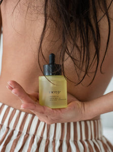 Woman holding hair and body oil bottle